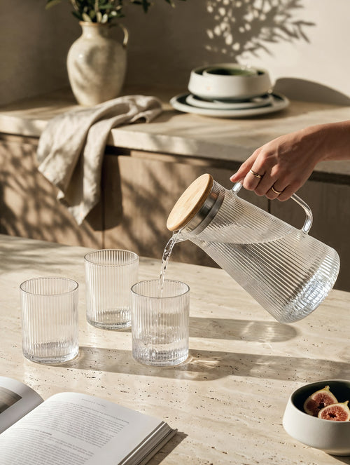 Glassware collection — ribbed carafe pouring water into tumblers