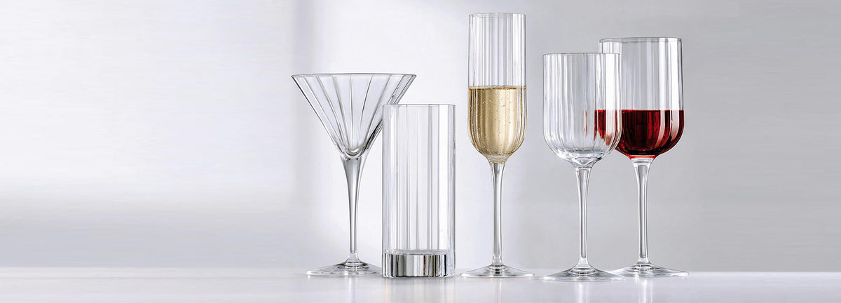 Line-up of fluted crystal glassware: martini, highball, champagne flute and wine glasses, set to the right of open space
